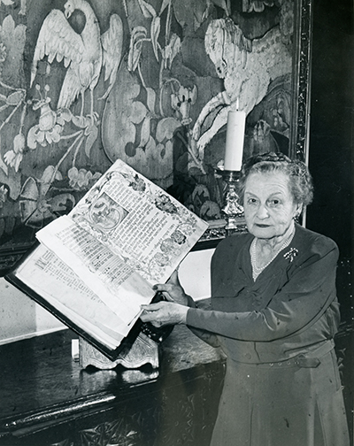 <p>Rachel Hunt (1882–1963), holding a Spanish manuscript of music dated 1458, bound over wood boards in red-tooled leather (now in Hunt Library's Fine and Rare Books Collection), ?at Elmhurst, 1962, photograph by Jones of East Liberty, HI Archives portrait no. 21.</p>